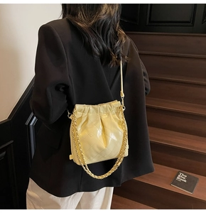 Detail of yellow quilted leather bucket bag with gold chain strap on a model's shoulder