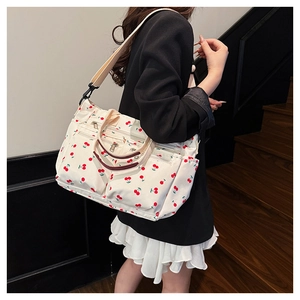 Détails d'un sac cabas blanc en toile avec motifs cerises et poches zippées