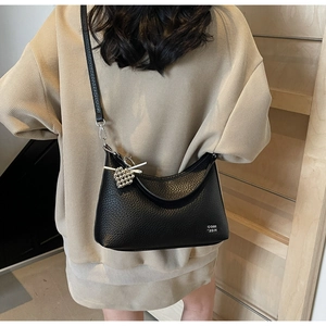 Detail of black pebbled leather half-moon shoulder bag with silver heart charm and logo