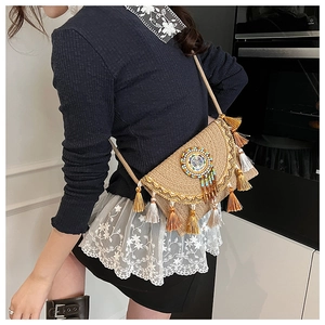 Detail of bohemian woven shoulder bag featuring colorful beaded disc and tiered fringe trim