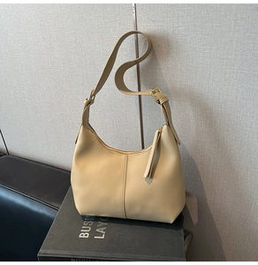 Detail of beige leather shoulder bag featuring gold hardware and leather tassel zip