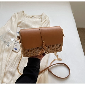 Close-up of woven straw and brown leather shoulder bag with golden ring hardware