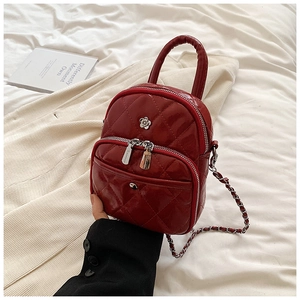 Detail of burgundy quilted faux leather mini bag with chain strap and silver floral logo