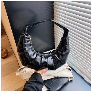 Detail of black pleated hobo bag showing glossy patent finish and layered textures