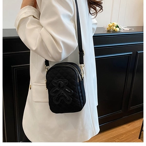 Quilted black crossbody phone bag with bear detail on a white blazer outfit