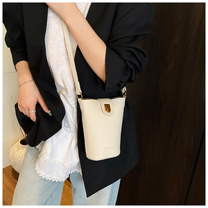 White lychee leather bucket bag with gold clasp shown on model for size and fit