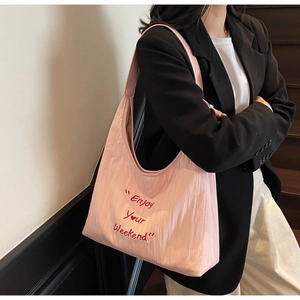Detailed embroidery of 'Enjoy Your Weekend' text on pink canvas tote bag side view