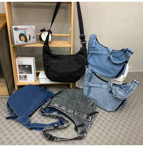 Collection of denim crescent crossbody bags in various washes with adjustable straps