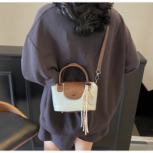 Detail of mint green and brown handbag with tennis racket charm worn by a model