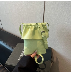 Gros plan du petit sac bandoulière vert clair à texture litchi et détails de volants