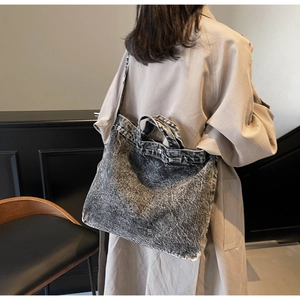 Retro grey washed denim tote bag shown with shoulder strap on a model wearing a trench coat