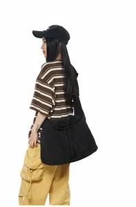 Vue latérale du grand sac bandoulière noir à cordon avec t-shirt rayé et pantalon cargo jaune