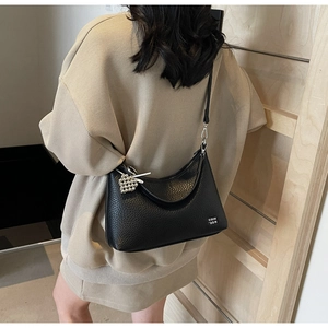 Black pebbled leather crescent tote bag with silver heart charm on model back view