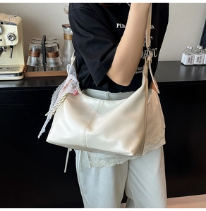 Detail of creamy white shoulder bag featuring lace decoration and smooth texture