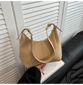 Close-up of beige minimalist leather shoulder bag with adjustable strap and zipper details