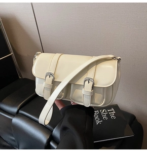 Detail of cream leather rectangular shoulder bag featuring vintage double buckle closure