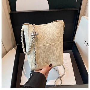Detail of off-white lychee leather bucket bag with silver chain and metal ball clasp