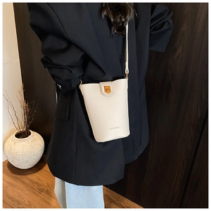 Detail of cream white pebbled leather bucket bag worn by model showing its actual size