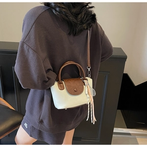 Detail view of a two-tone crossbody bag with badminton racket charm and adjustable strap