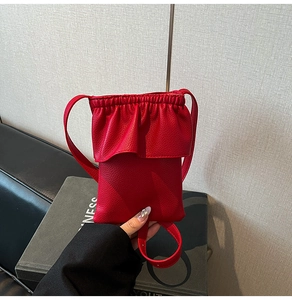 Détail du mini sac bandoulière rouge texture litchi avec design élégant à volants