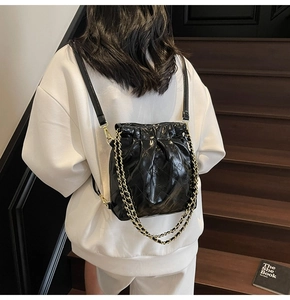Detailed view of the quilted black drawstring backpack with elegant metal chain straps