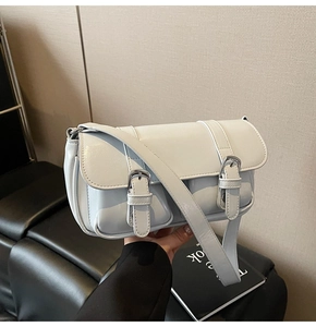Detailed view of luxury square shoulder bag with silver buckles and glossy leather texture