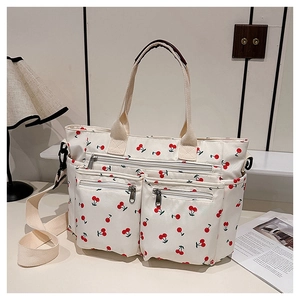 Détail du sac cabas en toile blanche à imprimé cerise avec poches zippées frontales