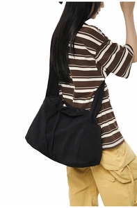Détail du sac bandoulière en nylon noir avec fermeture à cordon et large sangle réglable