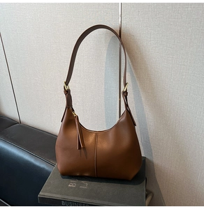 Detail view of smooth dark brown crescent shoulder bag with vertical seam and leather puller