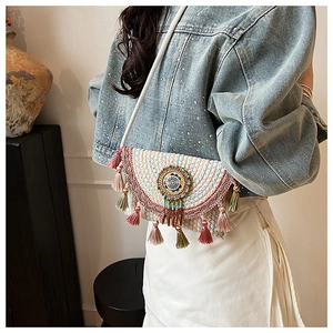 Detail of bohemian knit crossbody bag with colorful embroidery and tassel trim on a model