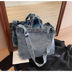 Close-up of vintage blue washed denim tote bag with metal snap and adjustable strap