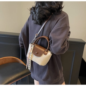 Detailed view of beige canvas crossbody bag with brown leather flap and stylish cord charm