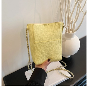 Detailed close-up of light yellow bucket bag with lychee texture and chain strap