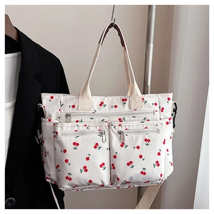 Détail du sac fourre-tout blanc à imprimé cerise avec plusieurs poches zippées devant
