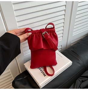 Détail du petit sac bandoulière rouge avec texture litchi et design à volants