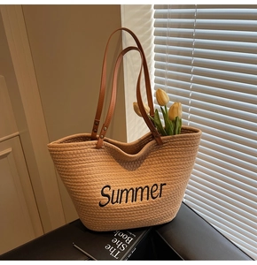 Détail d'un sac cabas en paille avec broderie Summer noire et anses en cuir marron