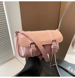 Detail of pink glossy leather handbag with double buckle flap in lifestyle setting