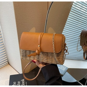 Detail of straw woven crossbody bag with brown leather flap and gold chain strap
