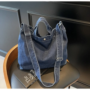 Detail view of deep blue denim tote bag with silver magnetic buckle and sturdy straps