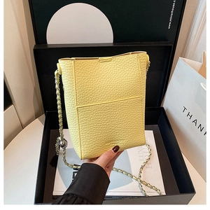 Close-up of lemon yellow lychee texture bucket bag with silver leather chain strap