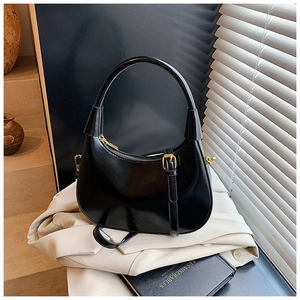 Dettaglio della borsa hobo nera con hardware dorato e logo del marchio sulla pelle