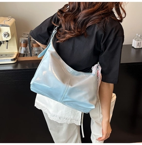Detail of light blue patent leather shoulder bag with white lace bow and V-shape stitching