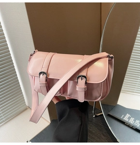 Close-up of pink glossy leather crossbody bag with vintage double strap buckle design