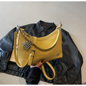 Detail of yellow lychee leather dumpling bag with silver heart charm and adjustable strap