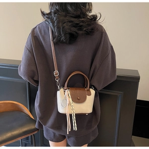 Detail of the mini color-block crossbody bag with racket pendant and woven tassel charm