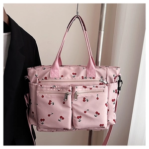 Détail du sac cabas en toile rose à motif cerises, poches zippées et bandoulière