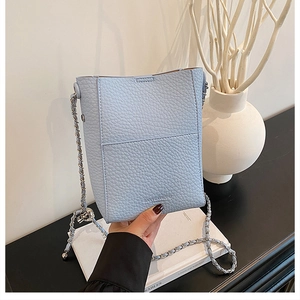 Close-up of light blue pebble leather crossbody bag with silver sphere charm detail