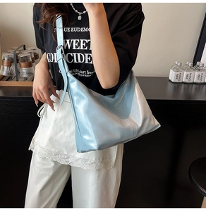 Detail of light blue glossy hobo bag with adjustable strap and silver metal buckle
