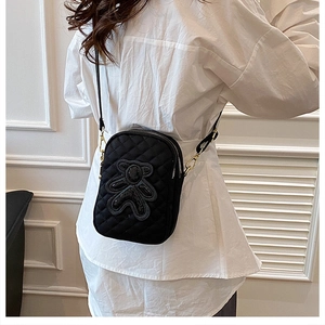 Back view of a black quilted nylon crossbody bag with cartoon bear on a model