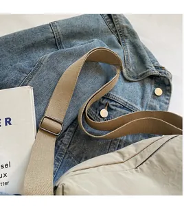 Close-up of adjustable fabric shoulder strap with metal buckle on beige crossbody bag